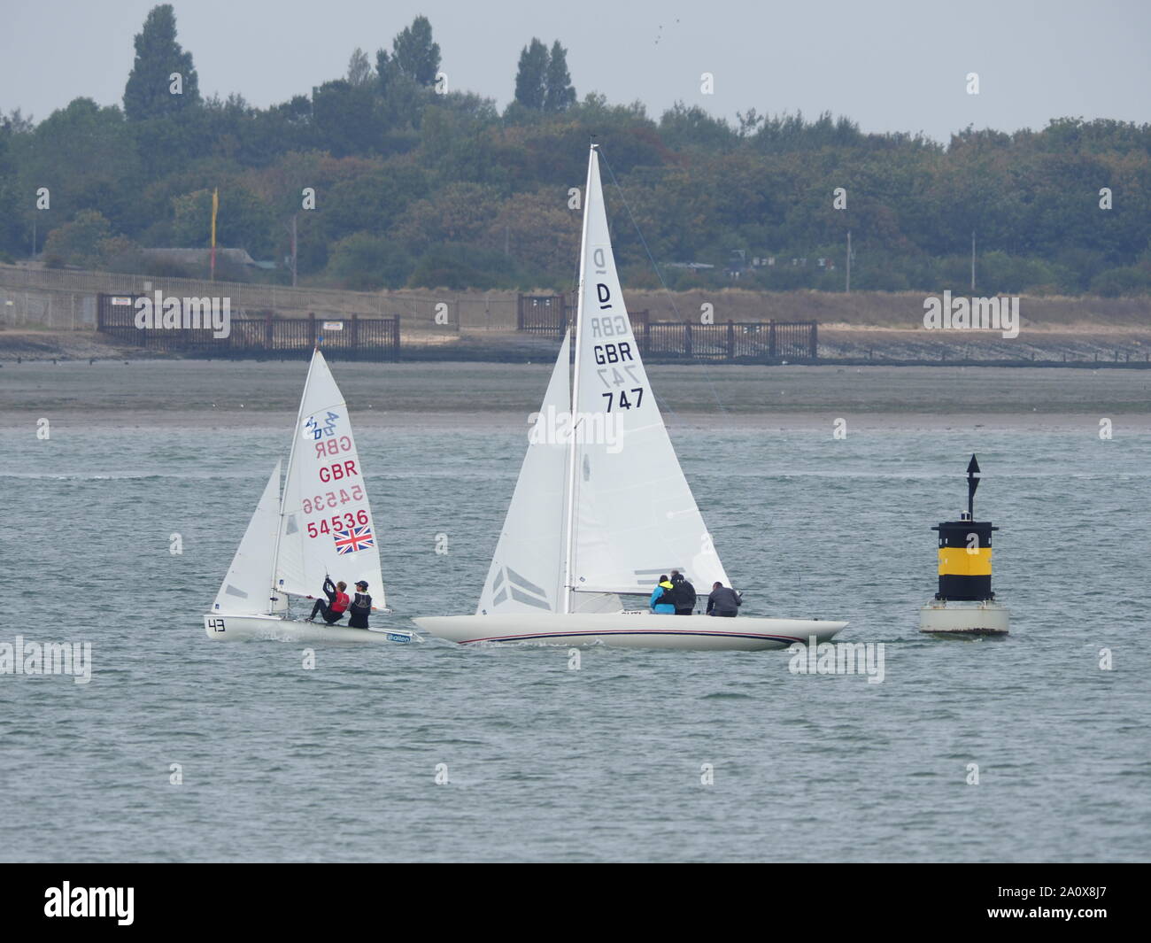 Queenborough, Kent, UK. 22nd September, 2019. 56th Medway Marathon - an annual 26 mile course on the tidal River Medway organised by Medway Yacht Club and open to both keelboats and sailing dinghies. The course starts at Upnor Rochester, and utilises various creeks on the Medway to make up the distance with the Queenborough Spit Buoy at the eastern extreme of the course. Pic: a 420 dinghy rounds the Queenborough Spit buoy ahead of a 3-person  Dragon keelboat. Credit: James Bell/Alamy Live News Stock Photo