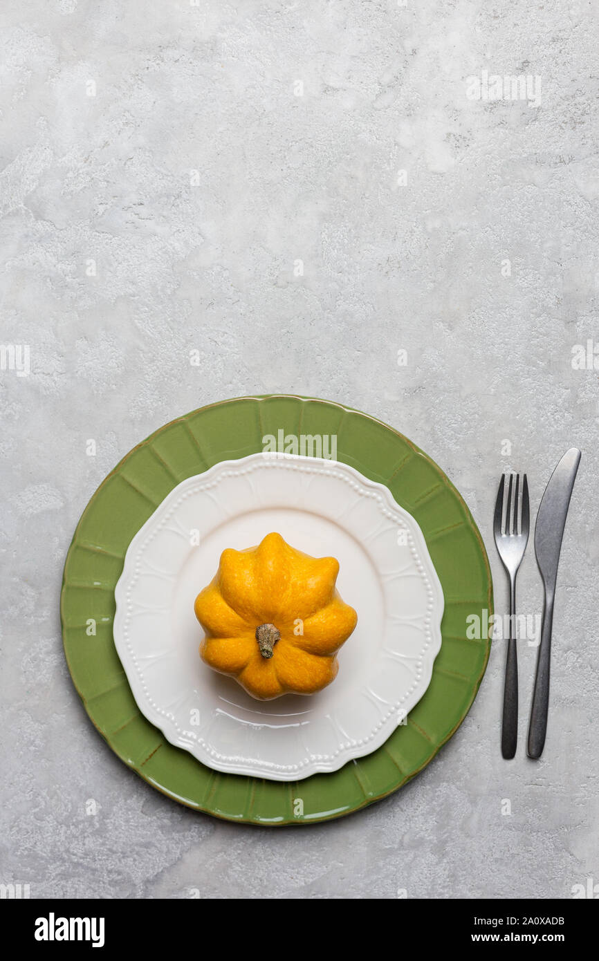 Autumnal serving plate at gray background with fork and knife with yellow decoration as pumpkin Stock Photo
