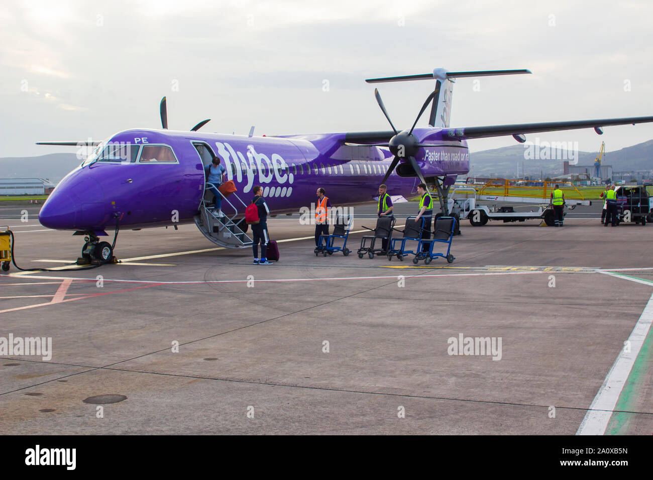 21 September 2019 A FlyBe Dash 8 Commercial Airliner with luggage and passenger handlers on the apron at George Best City Airport in Belfast Northern Stock Photo