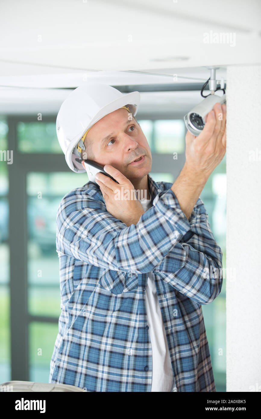 contractor by security camera talking on telephone Stock Photo