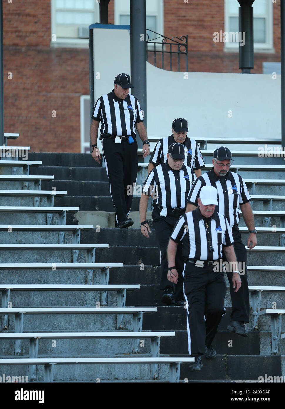 Football officials coming down stairs to the field at a high school