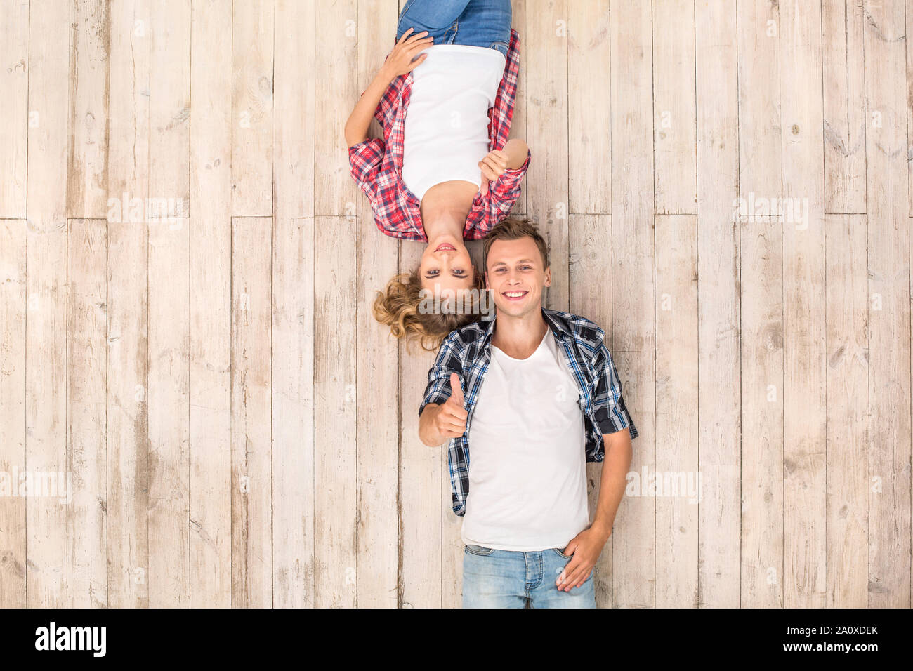 Freestyle. Young man and woman upside down lying on floor showing thumb ...