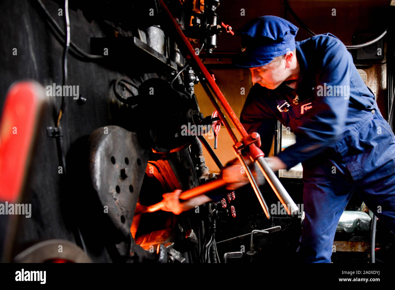 R761 Black and Red Steam Train with Driver Fireman Shovelling Coal into Fire, Southern Cross Station, Melbourne Victoria Australia Stock Photo