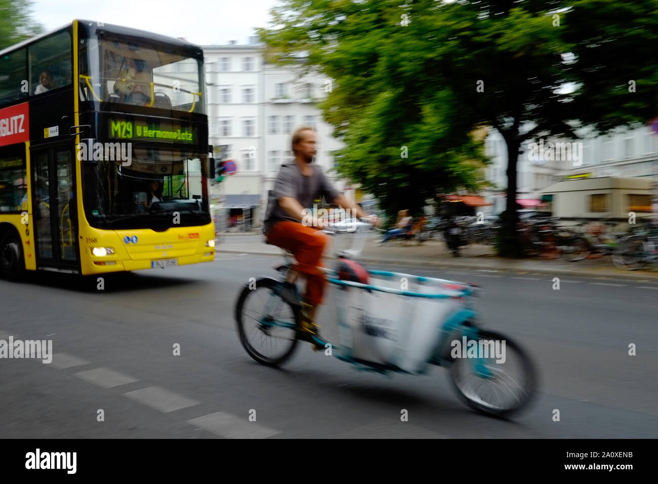 Berlin, Germany. 11th July, 2019. A young man rides a freight bike in front of a bus line M29 across Heinrichplatz in the district of Kreuzberg. Credit: Stefan Jaitner/dpa/Alamy Live News Stock Photo