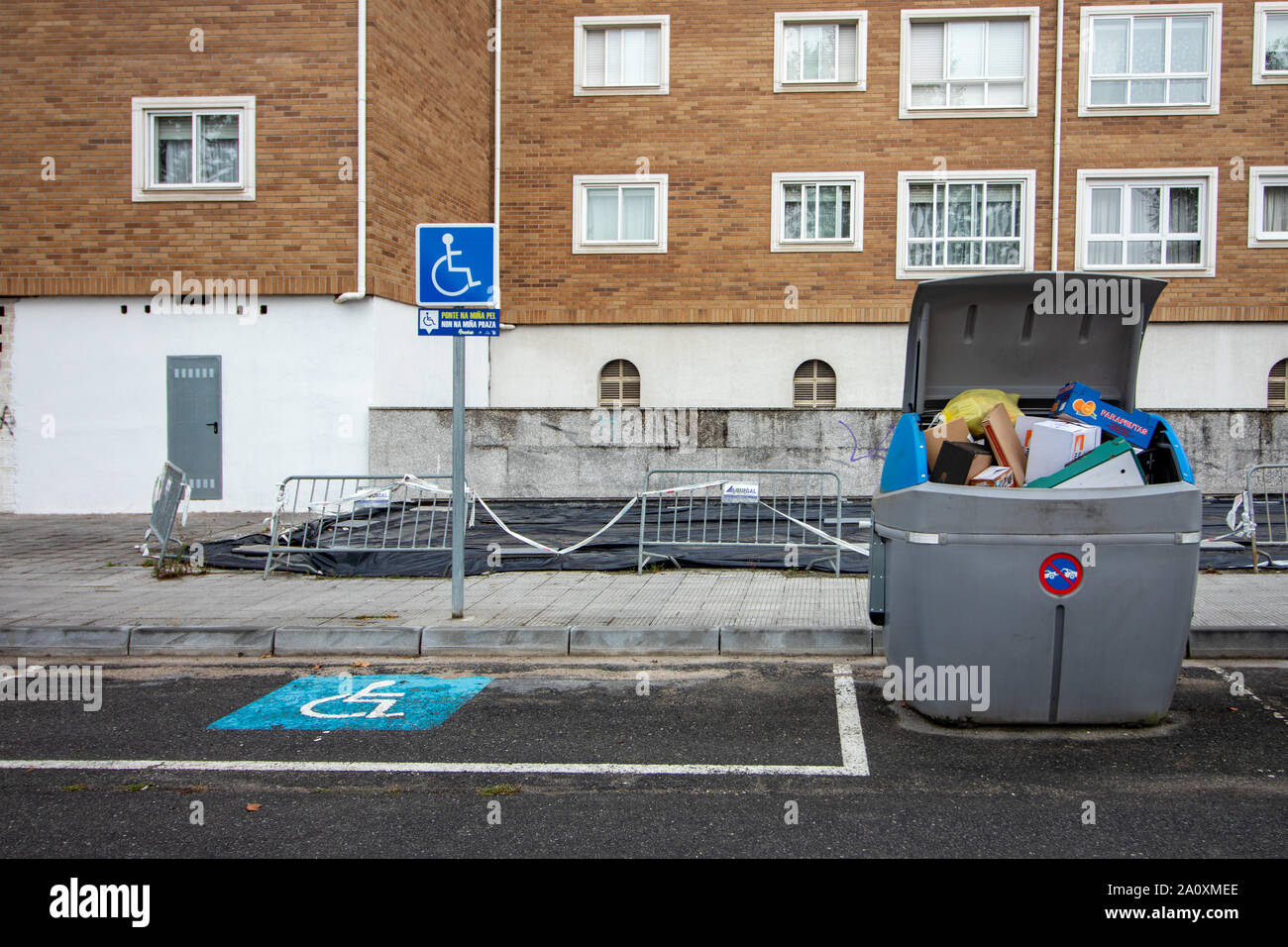 Coruna / Spain - September 20 2019: Disabled parking bay next to overflowing cardboard recycle bin in Coruna Spain Stock Photo