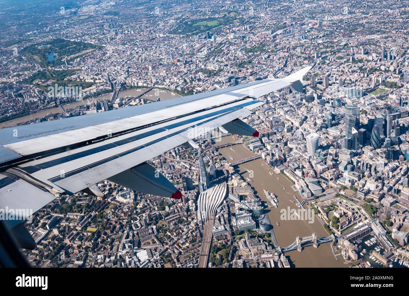 View from plane window with wing over Thames River, Tower Bridge, The Shard, Tower Bridge, Hyde Park & City of London, England, UK Stock Photo