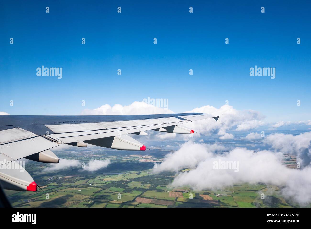 View from plane window flying above clouds and fields, Scotland, UK Stock Photo