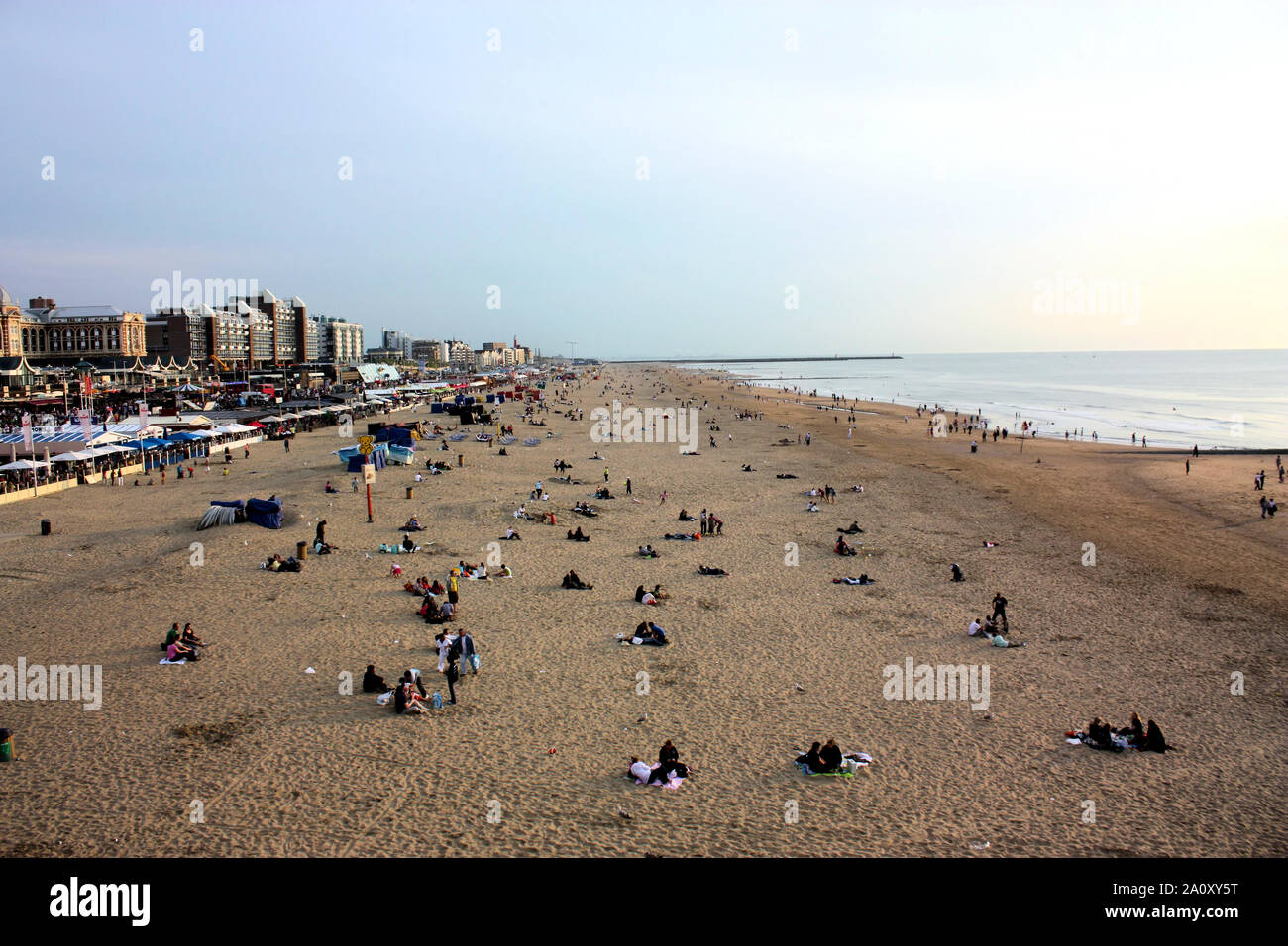 People like to enjoy the fresh open air in the summer evening at Scheveningen beach, the popular seaside resort in Holland. Stock Photo