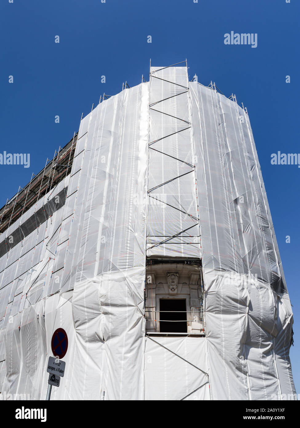 Building surrounded by scaffolding and protective plastic sheeting - Michaelerplatz, Vienna, Austria. Stock Photo