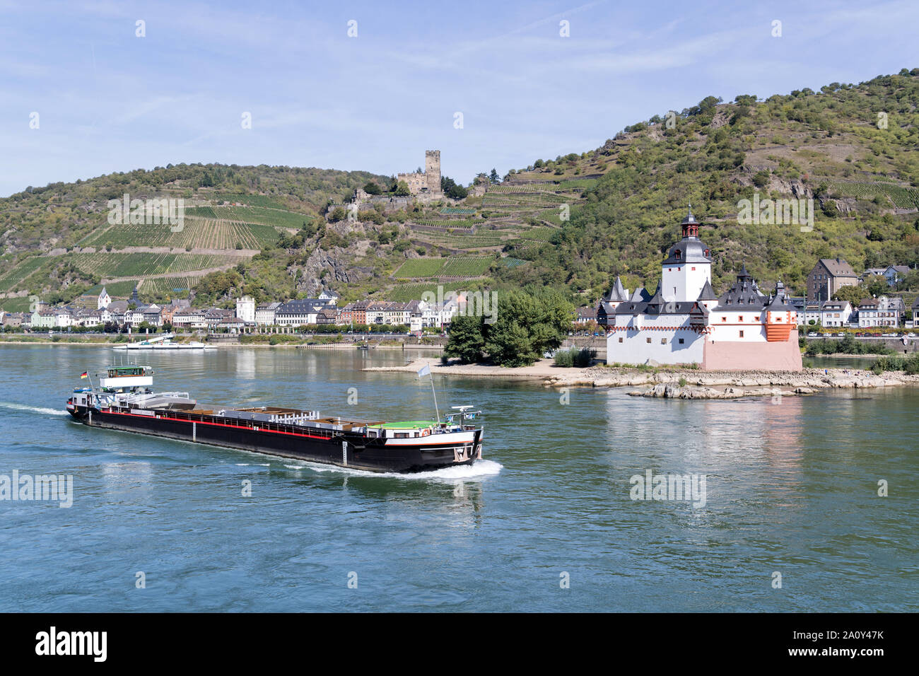 Inland general cargo vessel passing Pfalzgrafenstein Castle, a toll castle on the Falkenau island, in the River Rhine near Kaub, Germany. Stock Photo