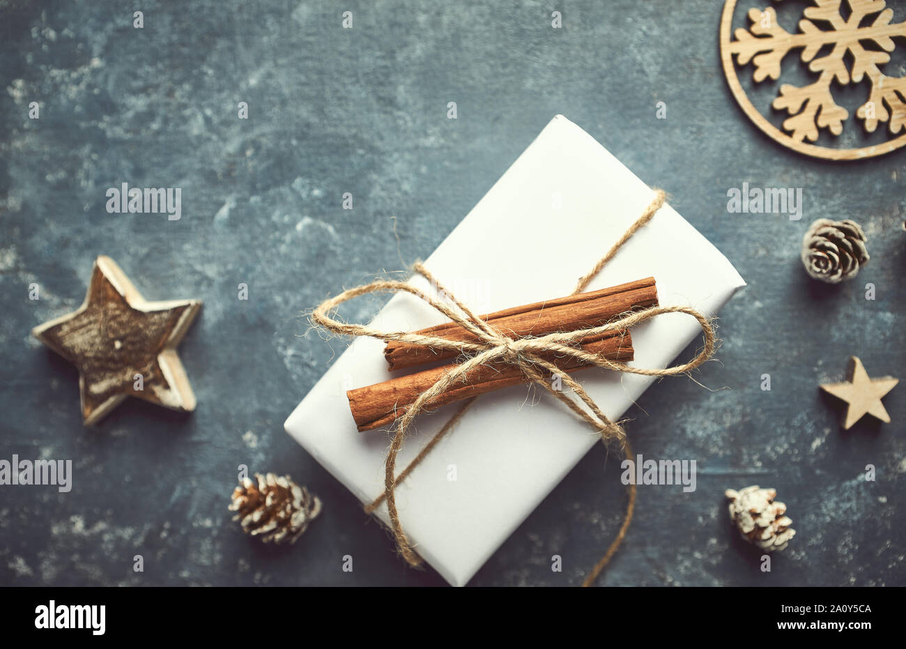Christmas present decorated with cinnamon sticks on gray background. Copy space. Flat lay Stock Photo