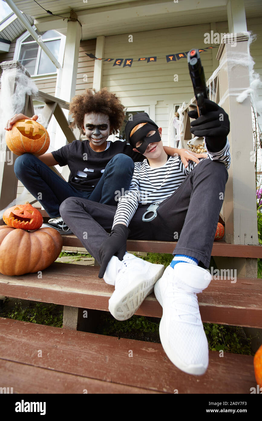 Low angle portrait of two teenage boys wearing Halloween costumes sitting  on porch of decorated house and looking at camera, copy space Stock Photo -  Alamy