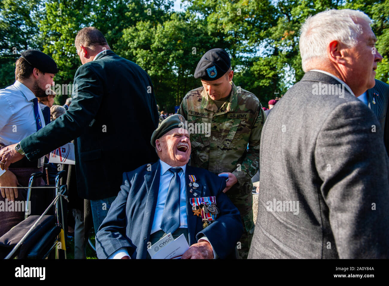 A war veteran having fun during the commemoration.At the Arnhem Oosterbeek War Cemetery, more than 1750 Allied soldiers were buried. As part of the commemorations for the 75th anniversary of Operation Market Garden, a memorial service was held in the presence of veterans, their relatives and thousands of people. A white stone arch was placed at each grave. On the field of honor is a 'Cross of sacrifice' made of Portland stone, on which a bronze sword is attached. Stock Photo