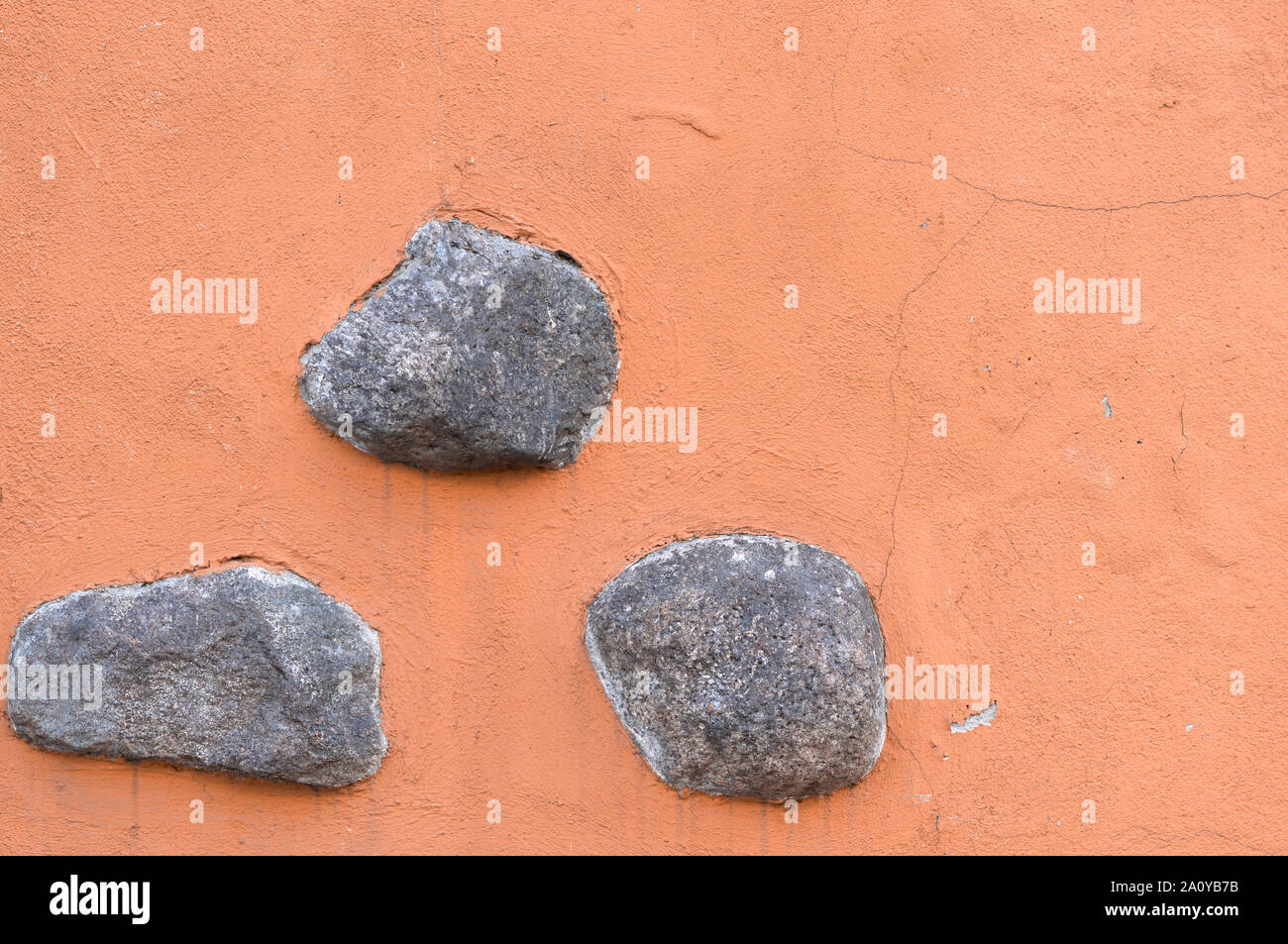 Three gray stones on an orange background. Stock Photo