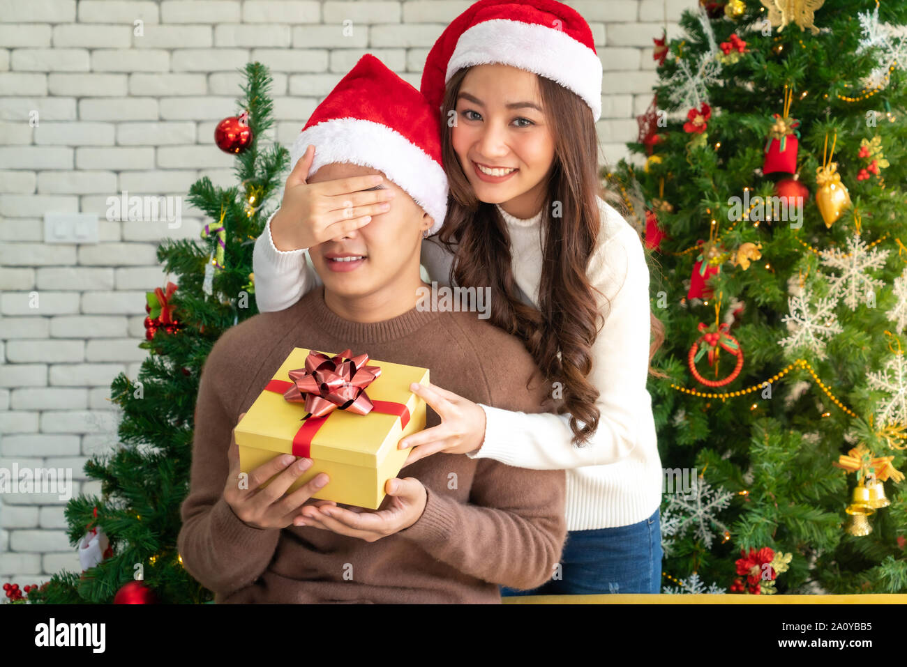 beautiful asian girl give surprise christmas gift to her boyfriend in Christmas holiday season greeting. Stock Photo