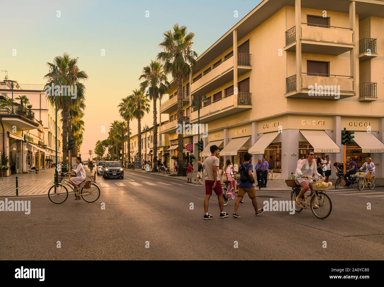 View of the centre of Forte dei Marmi with pedestrians and cyclists  crossing a palm tree-lined street at sunset, Lucca, Tuscany, Versilia,  Italy Stock Photo - Alamy