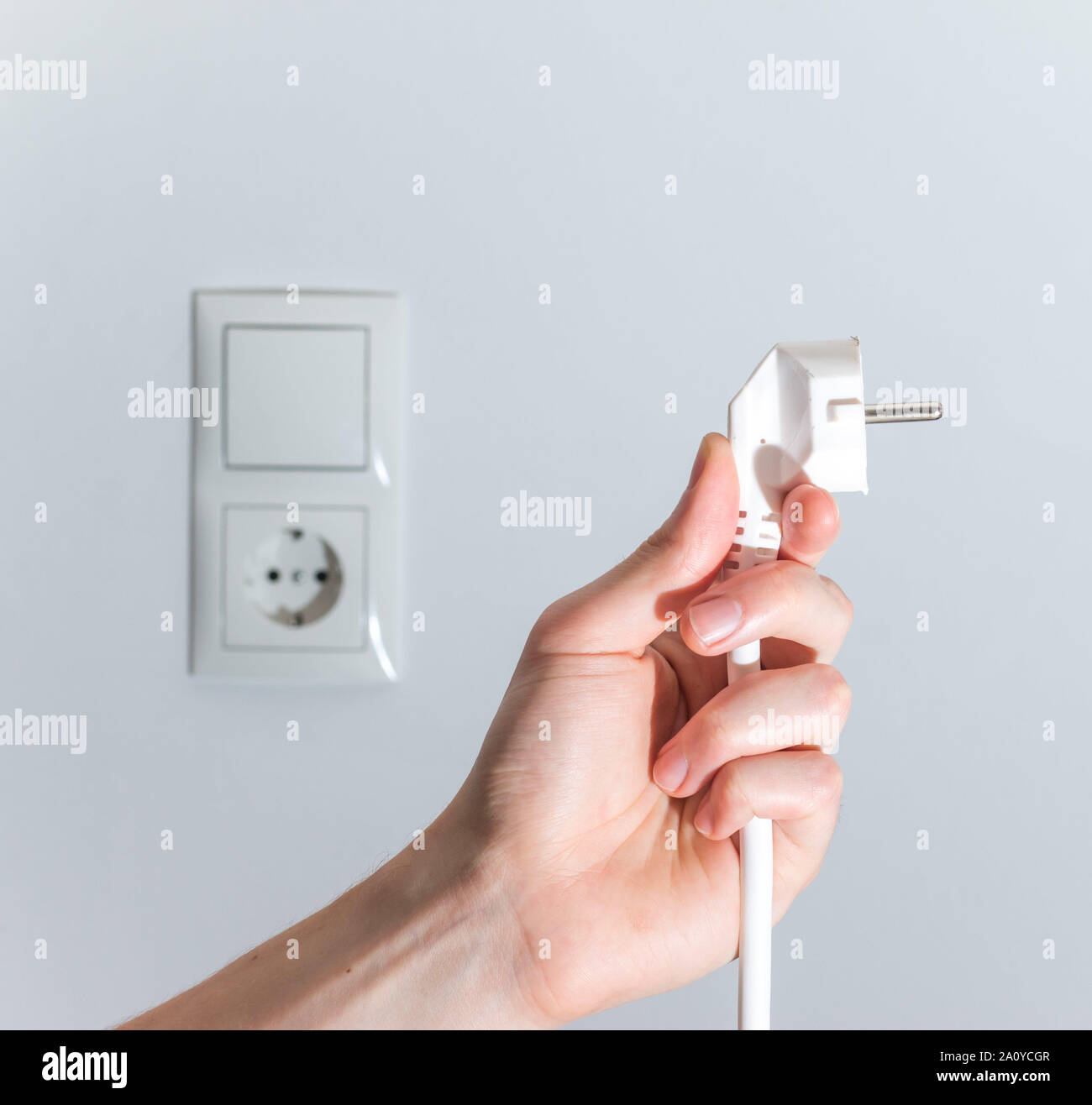 White plug with cable in males hand, ready to connect. Energy concept ...