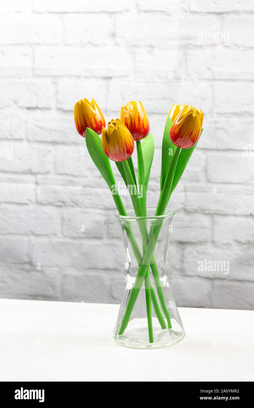 Yellow red artificial tulips in a transparent vase on a light