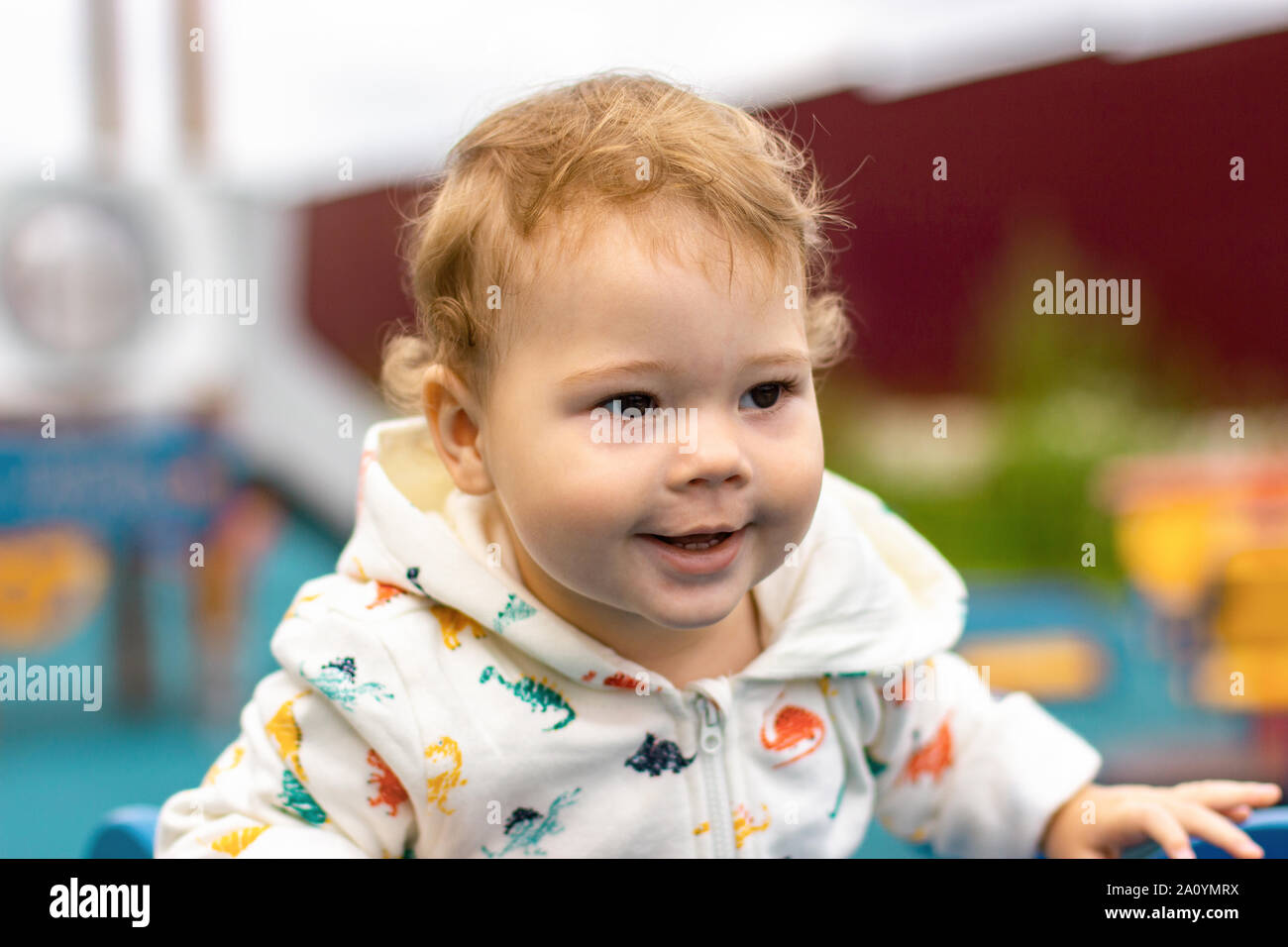 Portrait baby girl boy in white hoodie outdoor. Happy smiling Caucasian child 1 year old for a walk on the playground. Curly hair kid Stock Photo Alamy