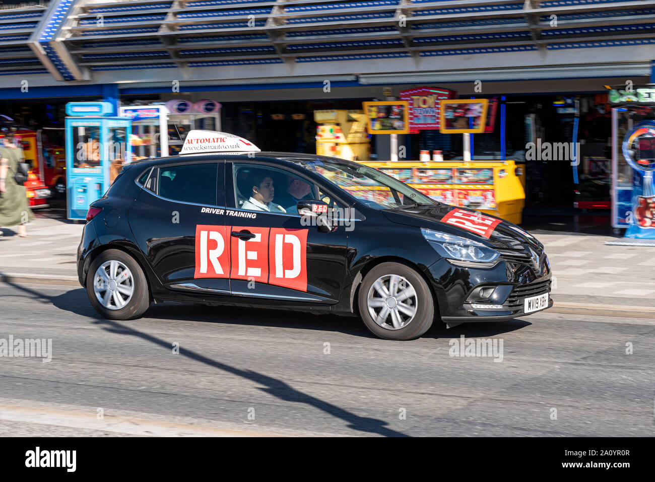 RED Driving School driving tuition car being driven by a learner driver along Marine Parade, Southend on Sea, Essex, UK passing amusement arcades Stock Photo