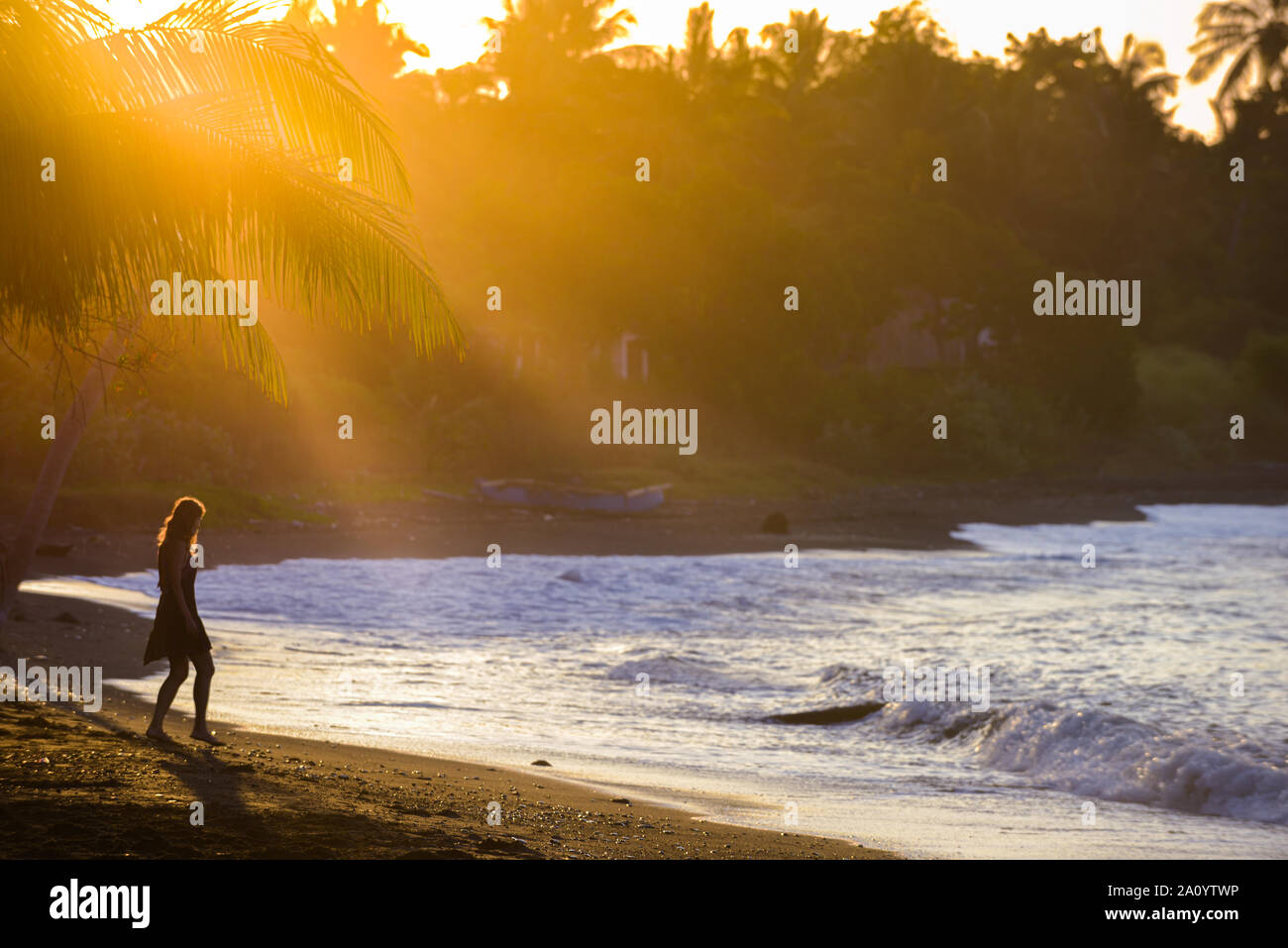 Young Woman walking down the beach at sunset, east side of Bali Indonesia Stock Photo