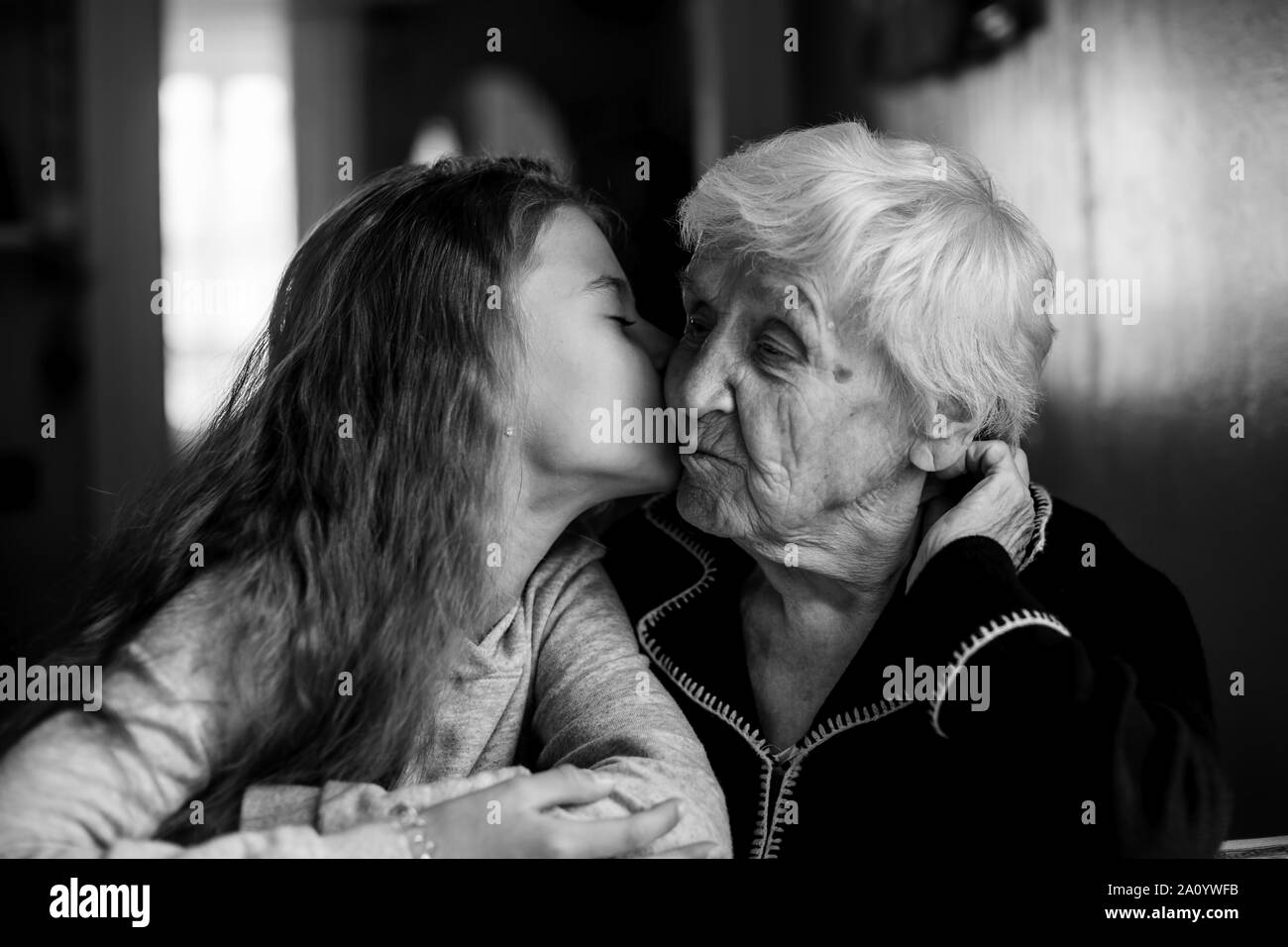 Elderly woman grandmother kiss with her little granddaughter. Black and white photo. Stock Photo