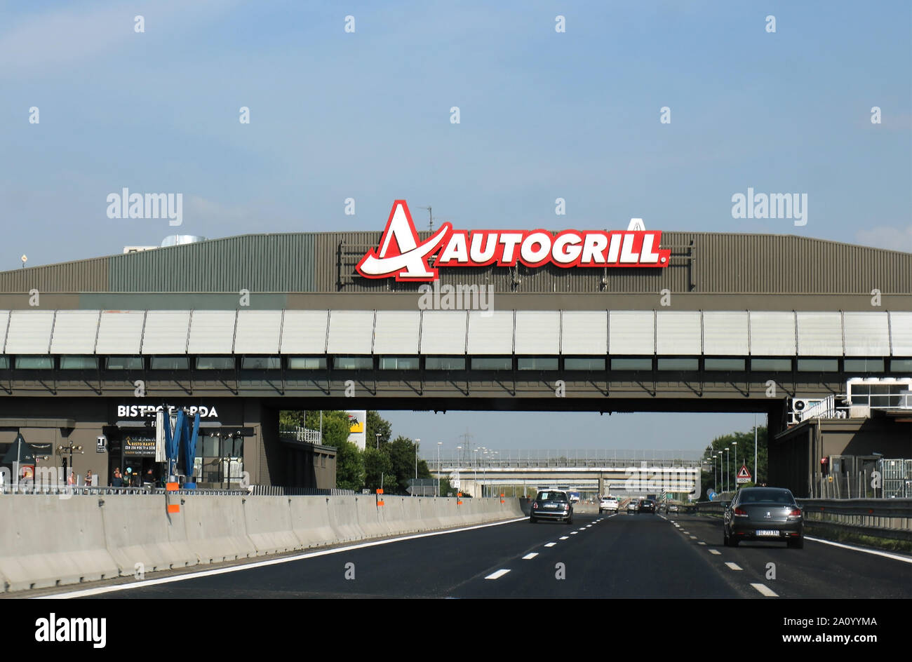 Milan, Italy - June 15, 2019: Highway on the way to Milan with cars on both sides of freeway and Autogrill restaurant with logo across on overlay brid Stock Photo