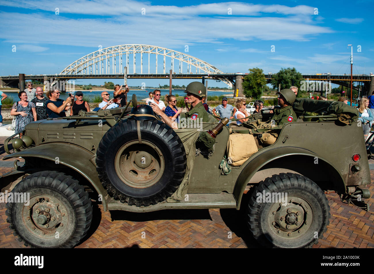 A military vehicle crossing the Waalkade, with the famous Waal bridge at the background during the parade.Military vehicle parade commemorating 75 years since Operation Market Garden took place. Operation Market Garden was one of the largest Allied operations of the Second World War. It took place on September 1944. At the time, the Allied Forces traveled from Belgium through several locations in the Netherlands, to finally end up in Nijmegen and Arnhem. The event started in the Belgian town of Leopoldsburg on September 14th. A military vehicle parade with around 600 army vehicles from the Sec Stock Photo