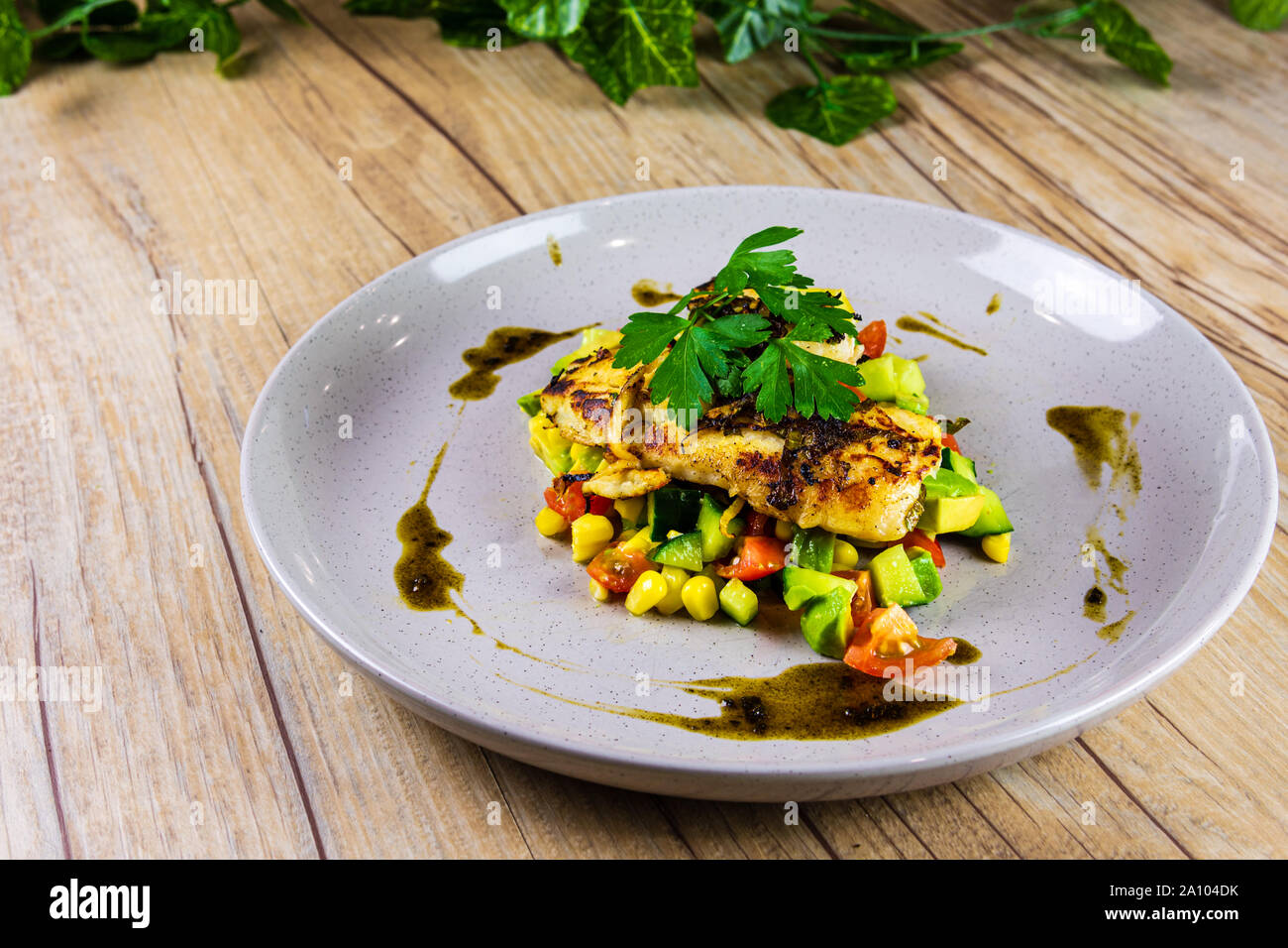 Grilled Fish on a bed of Salsa on a Grey Plate Stock Photo
