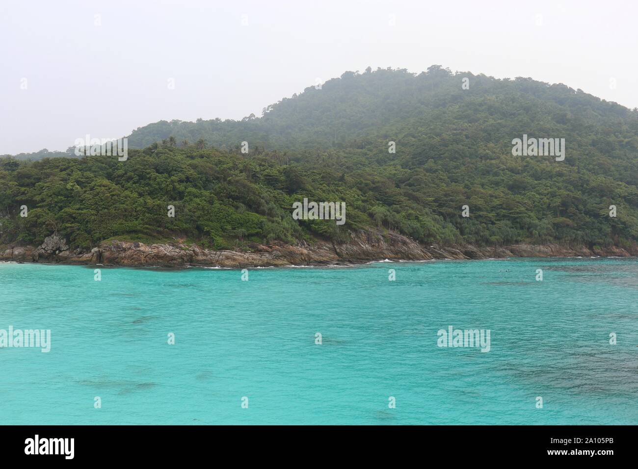 Tropical island, view to azure sea and green mountain covered with rainforest in the fog. Picturesque paradise landscape Stock Photo