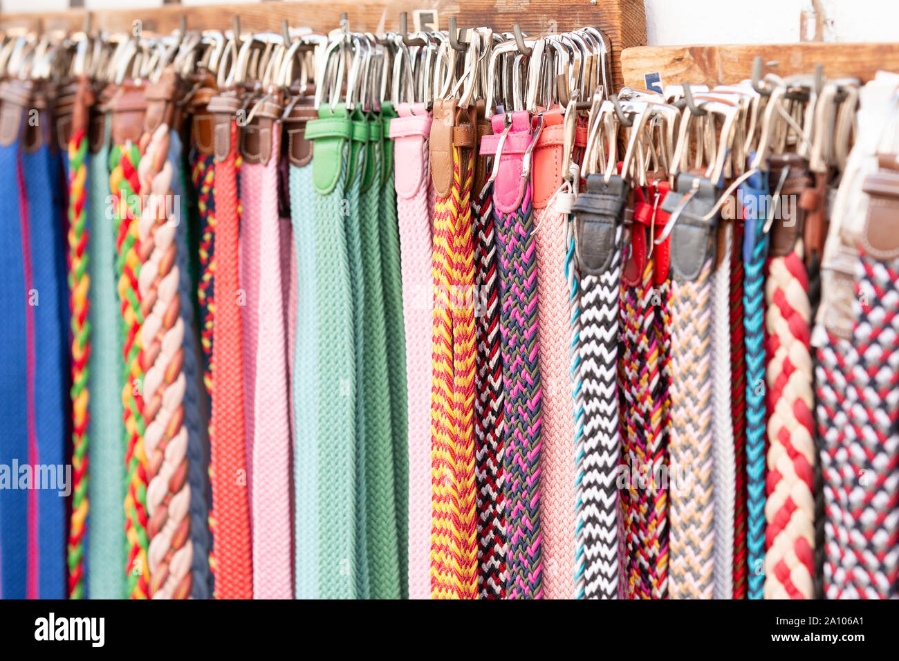 Bunch of assorted multicolored belts hanging on rack on market stall Stock Photo