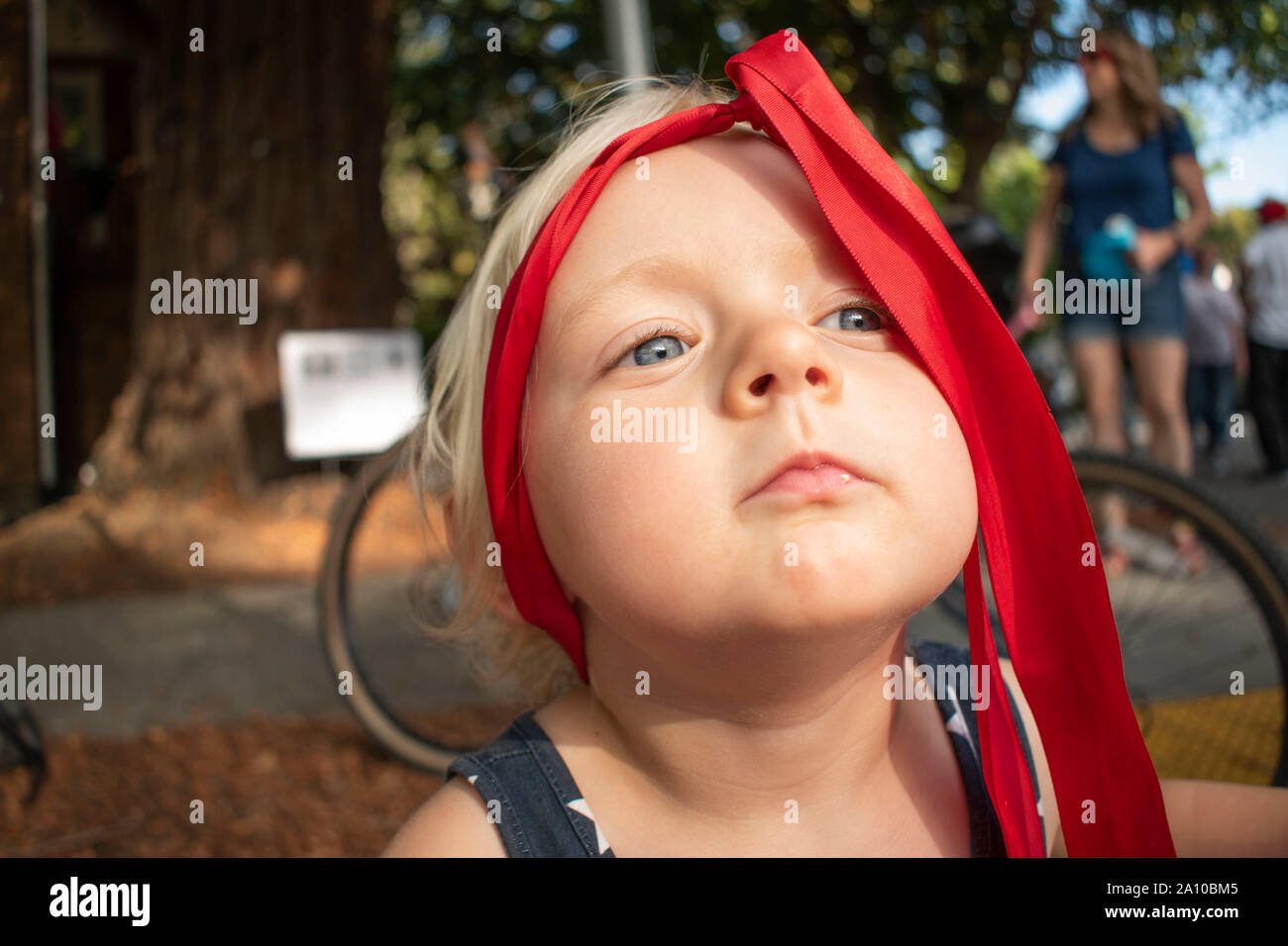 A young girl plays around with the ribbon on her head during a music festival in San Rafael, CA. Stock Photo