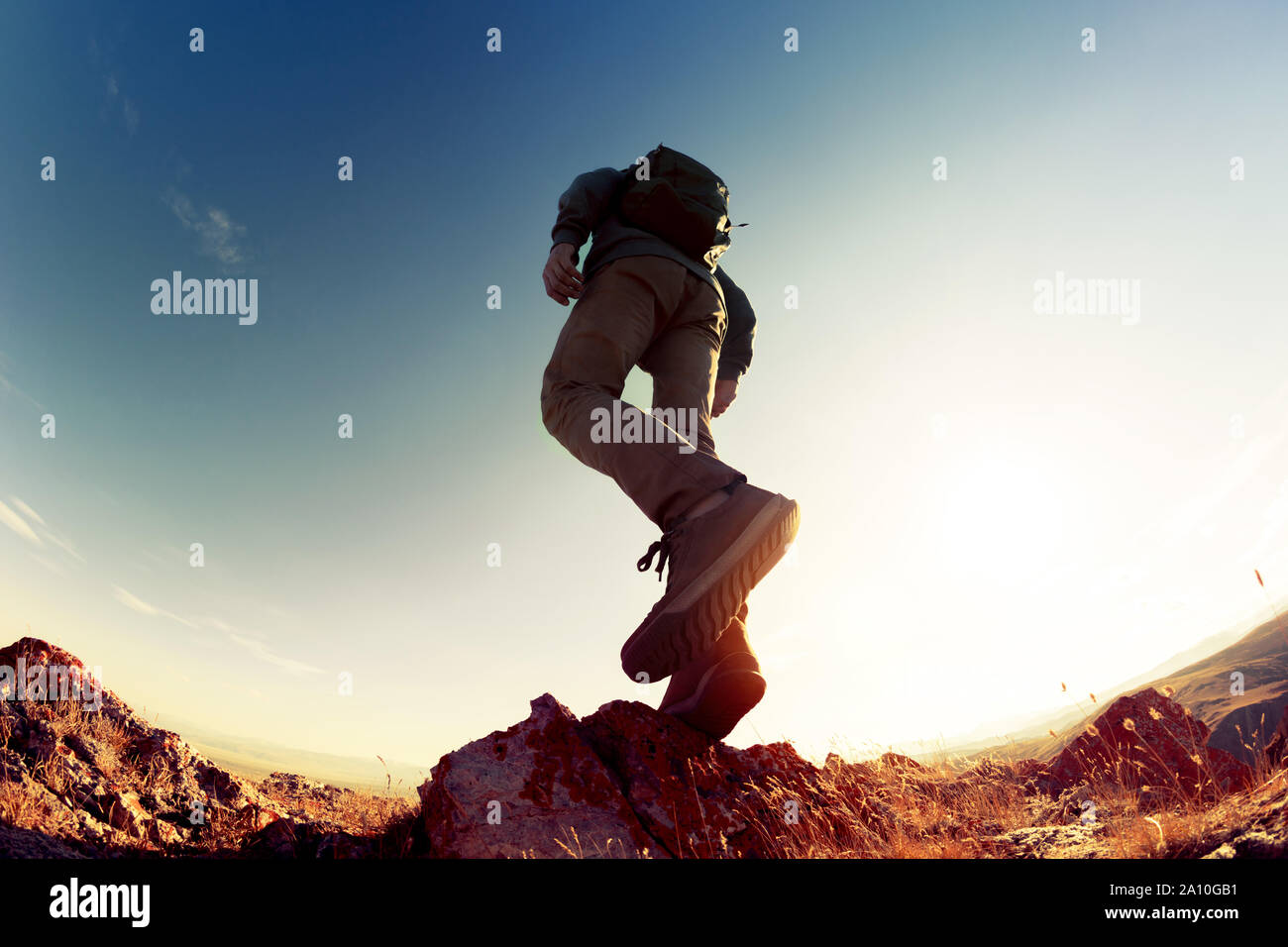 Silhouette of walking hiker with backpack in sunset light at mountains area. Closeup photo Stock Photo
