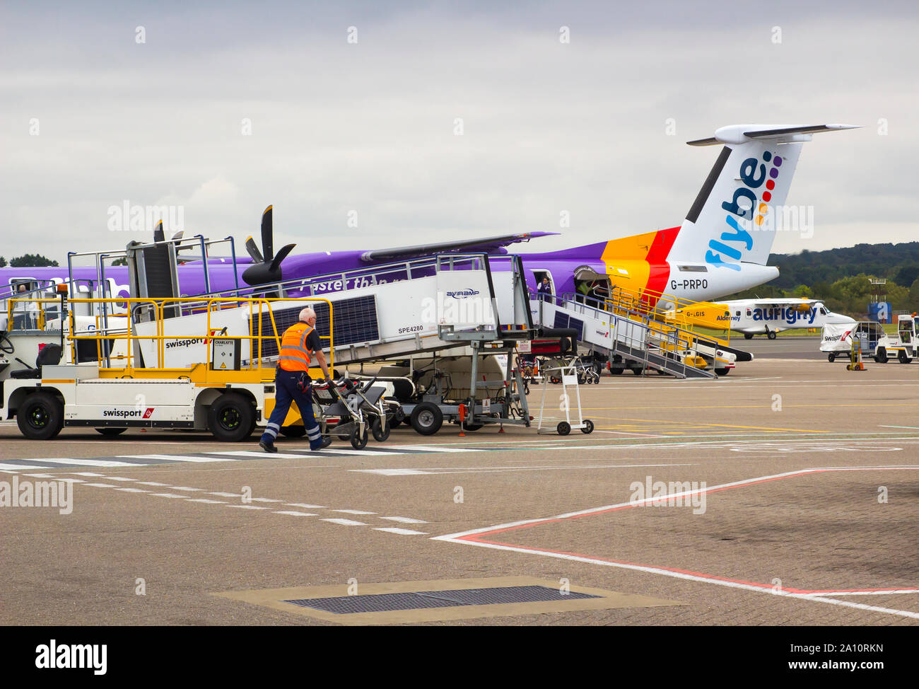 16 September 2019 Various baggage handling vehicles and loaders parked up iwith busy groundstaff n the early evening at Southampton Airport England Stock Photo