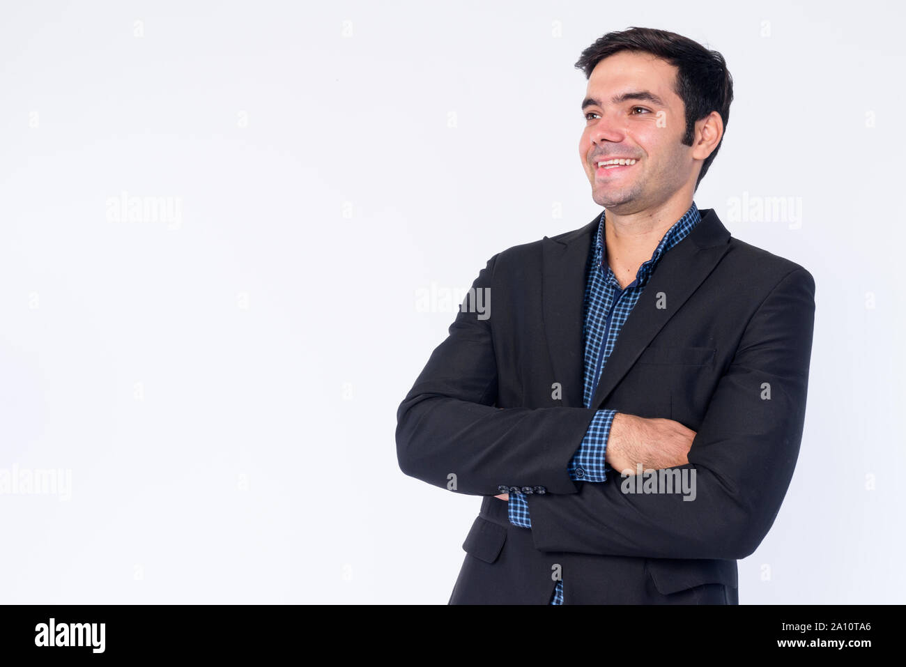 Portrait of happy young Persian businessman thinking with arms crossed ...
