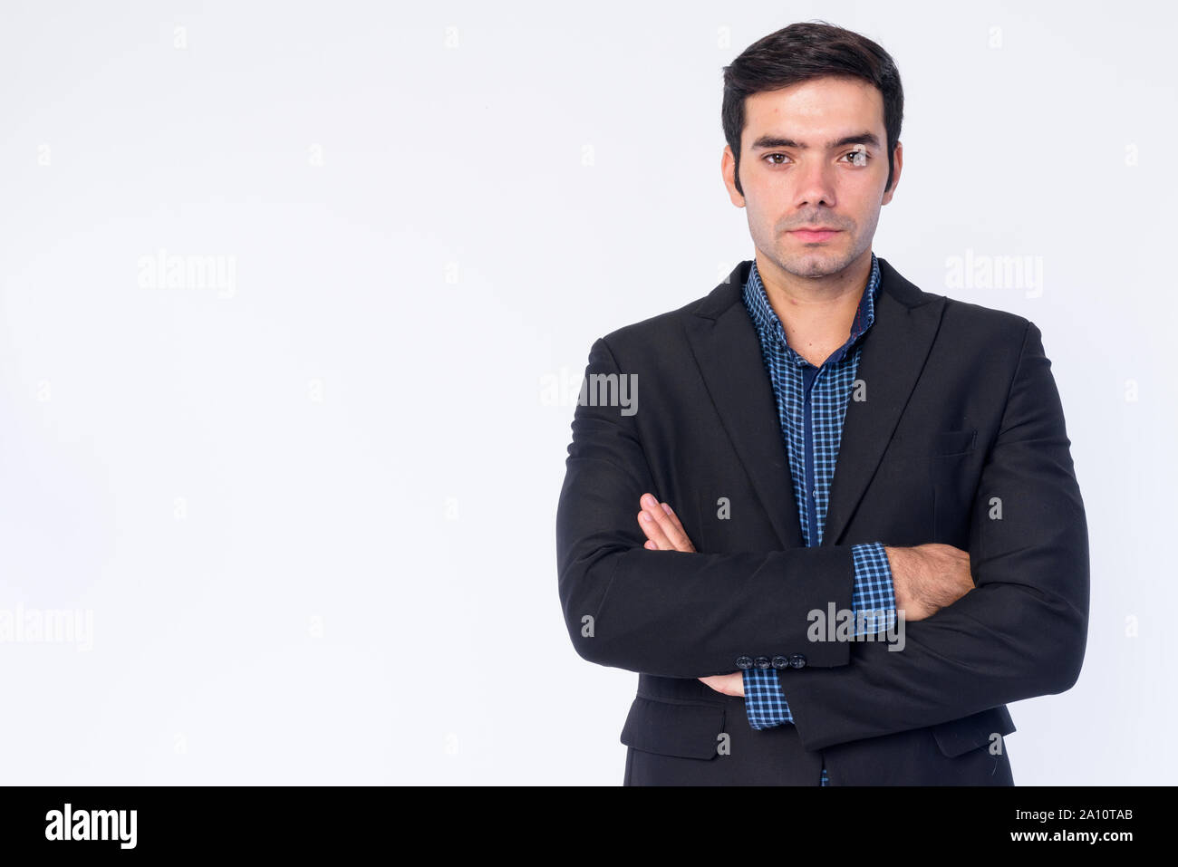 Portrait of young handsome Persian businessman in suit with arms ...