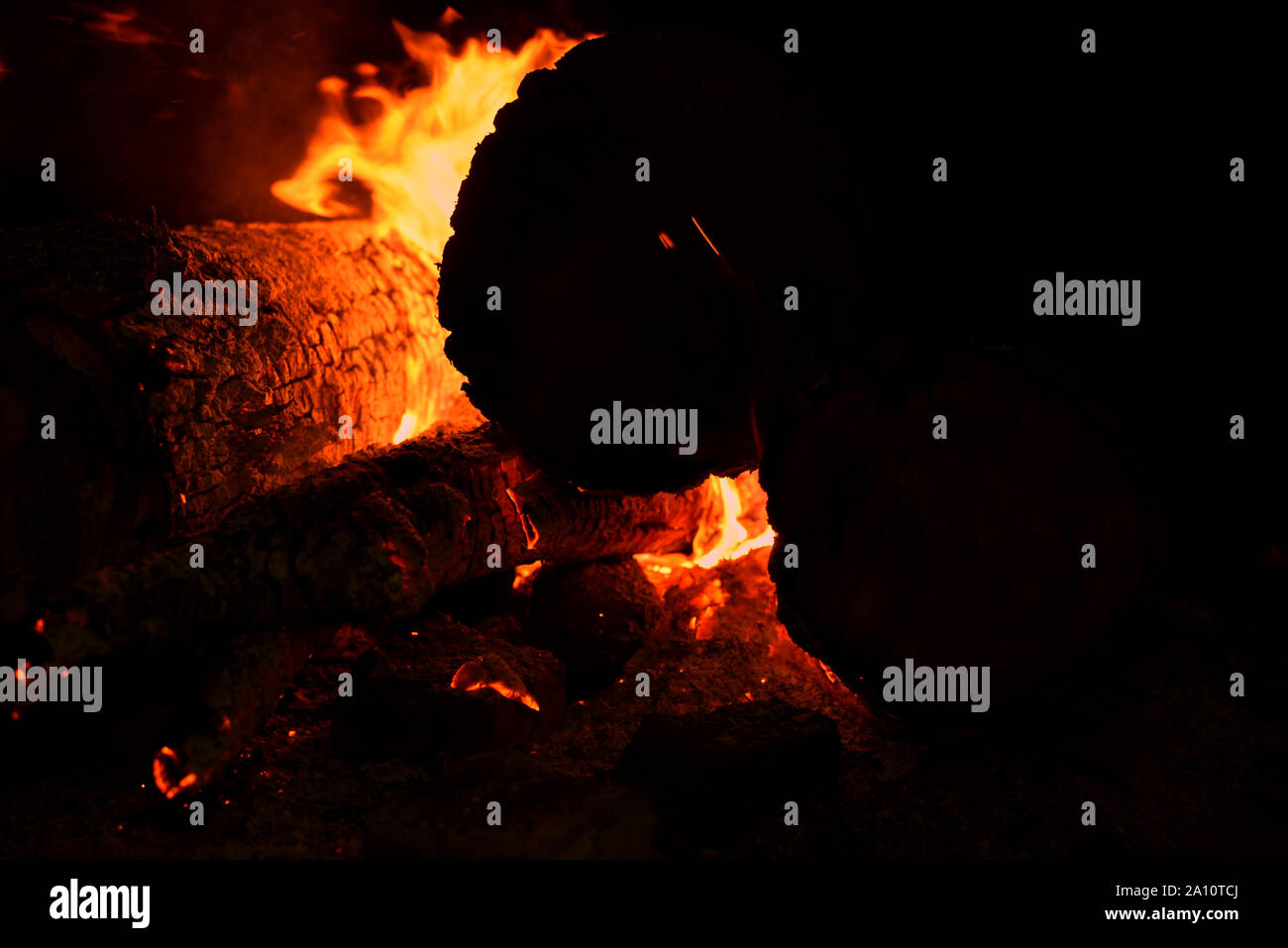 Close up of bonfire with sparks at night. Heat from burning logs and ...