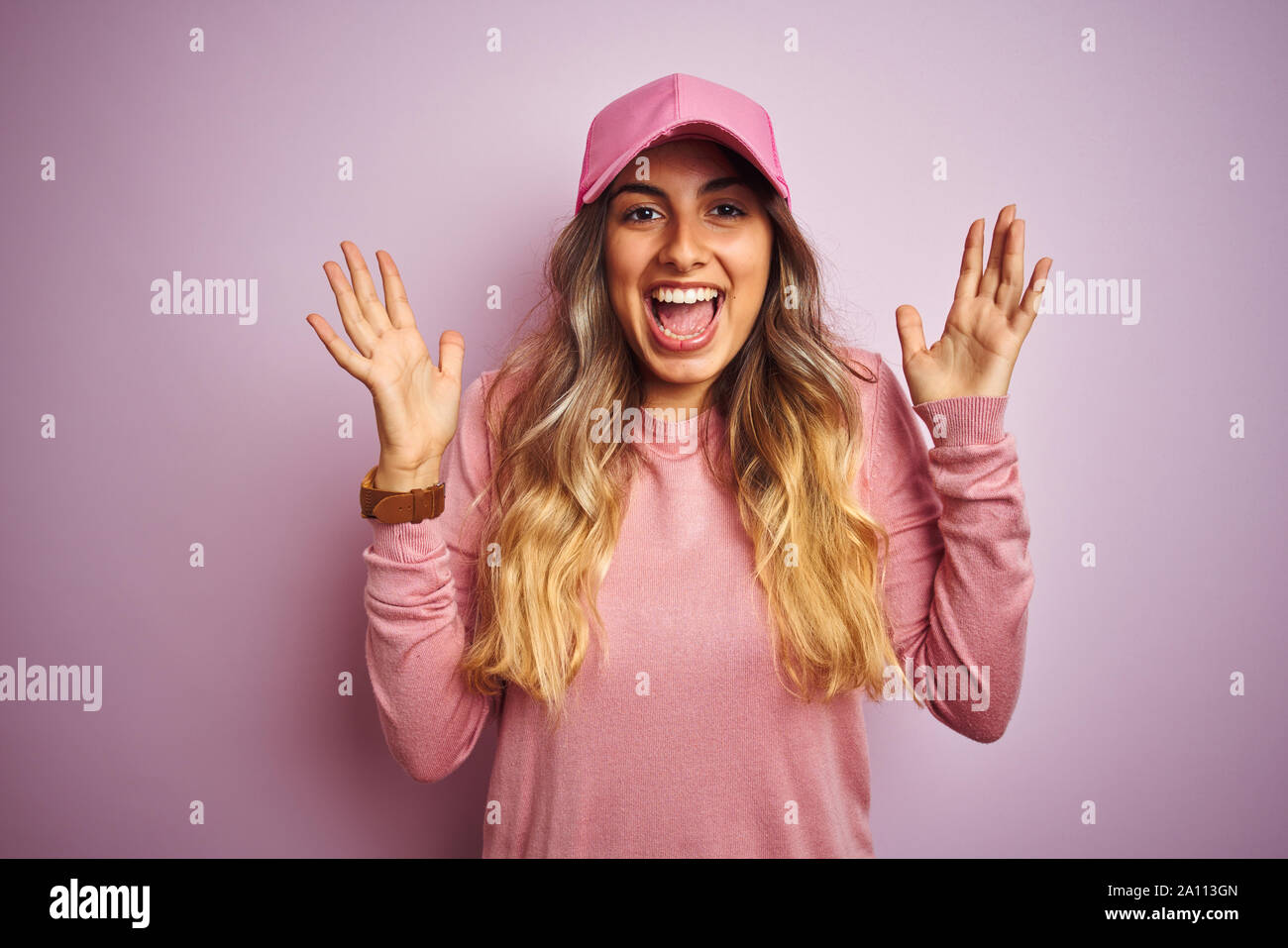 Young beautiful woman wearing cap over pink isolated background celebrating crazy and amazed for success with arms raised and open eyes screaming exci Stock Photo