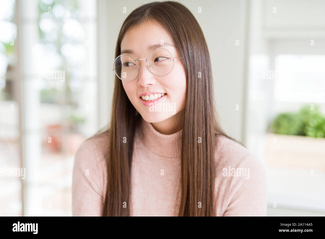 Beautiful Asian woman wearing glasses smiling looking side and staring ...
