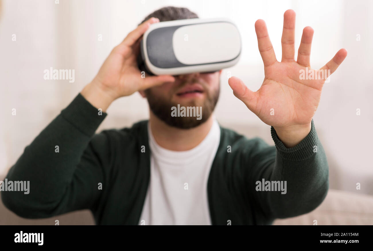 Man using vr glasses at home, looking at his hand Stock Photo