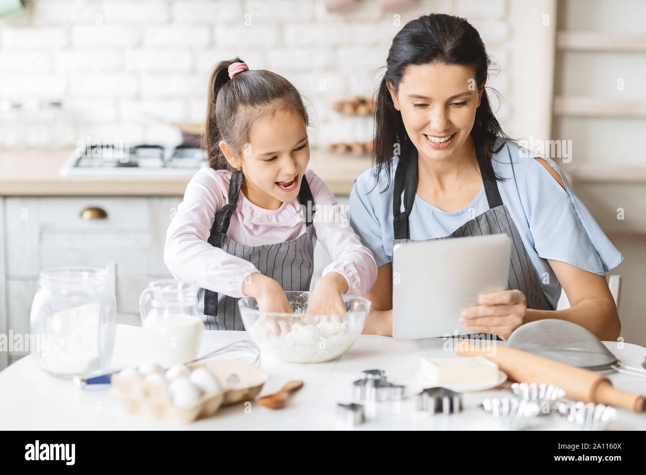 Mother and daughter using digital tablet in kitchen, looking recipe Stock Photo