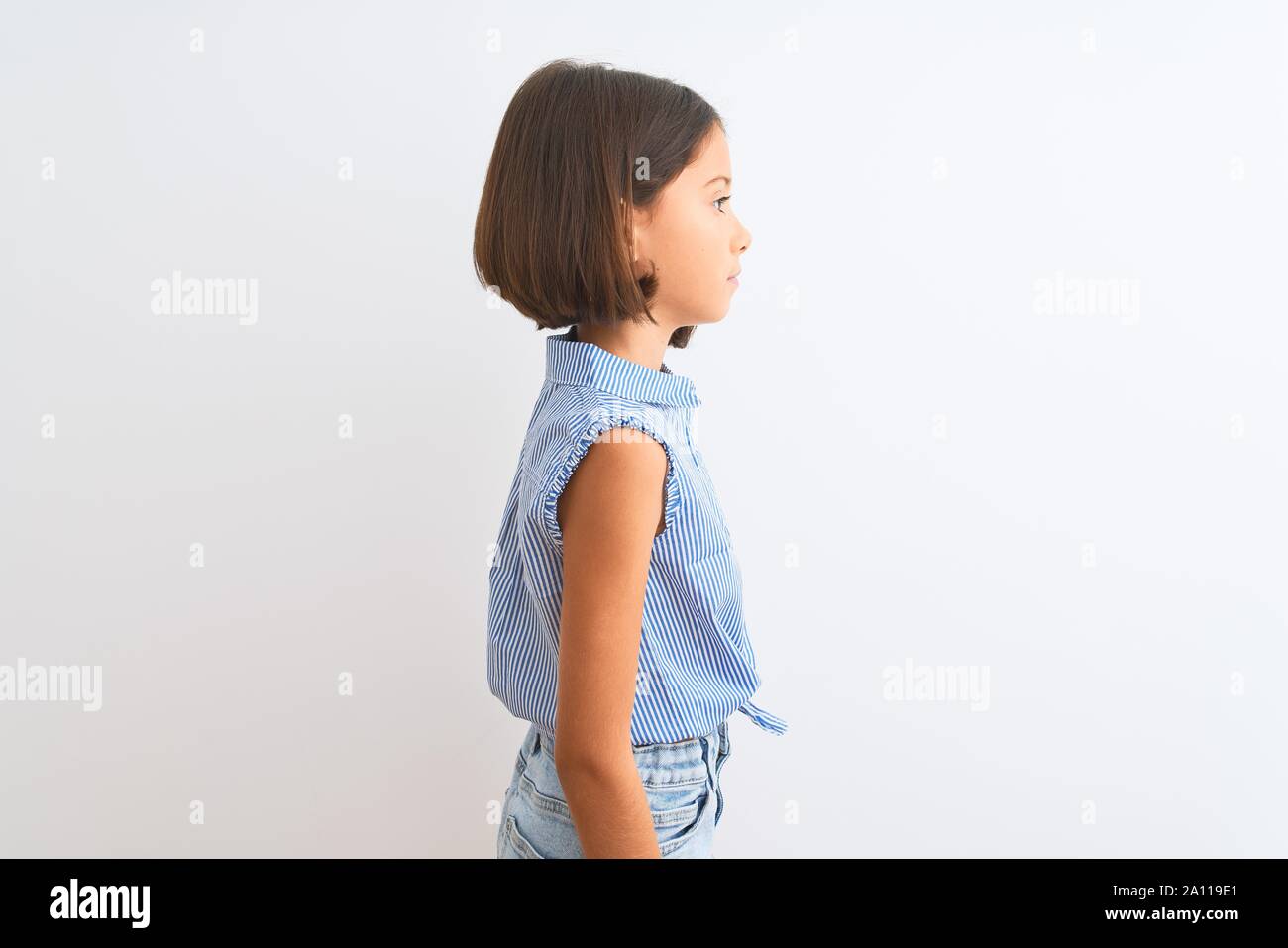 Young beautiful child girl wearing blue casual shirt standing over