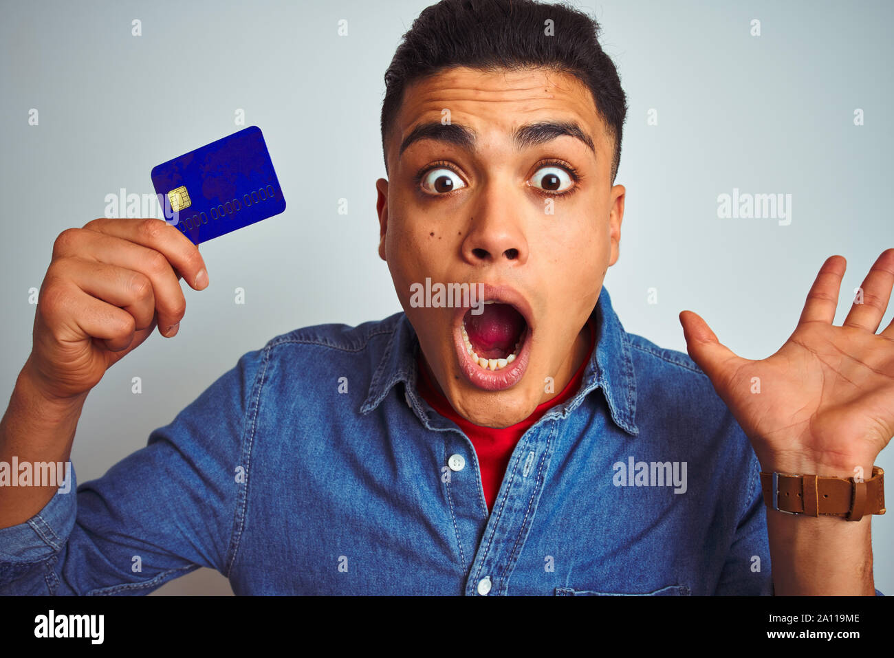 Young brazilian customer man holding credit card standing over isolated ...