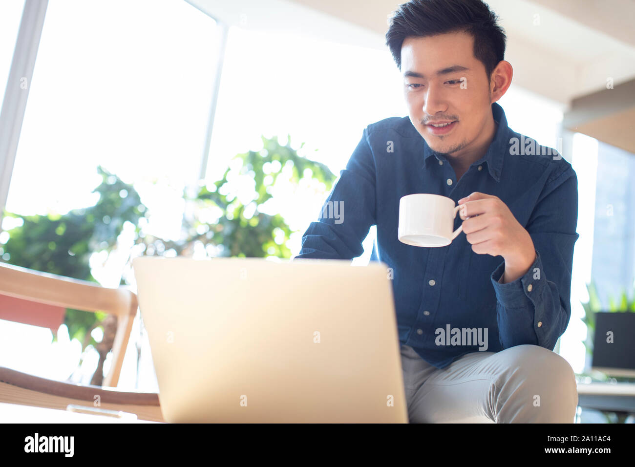 Young man using laptop and drinking coffee Stock Photo