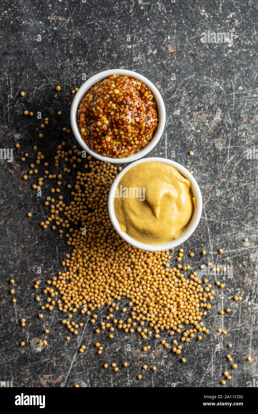 Yellow mustard and whole grain mustard and mustard seeds on kitchen