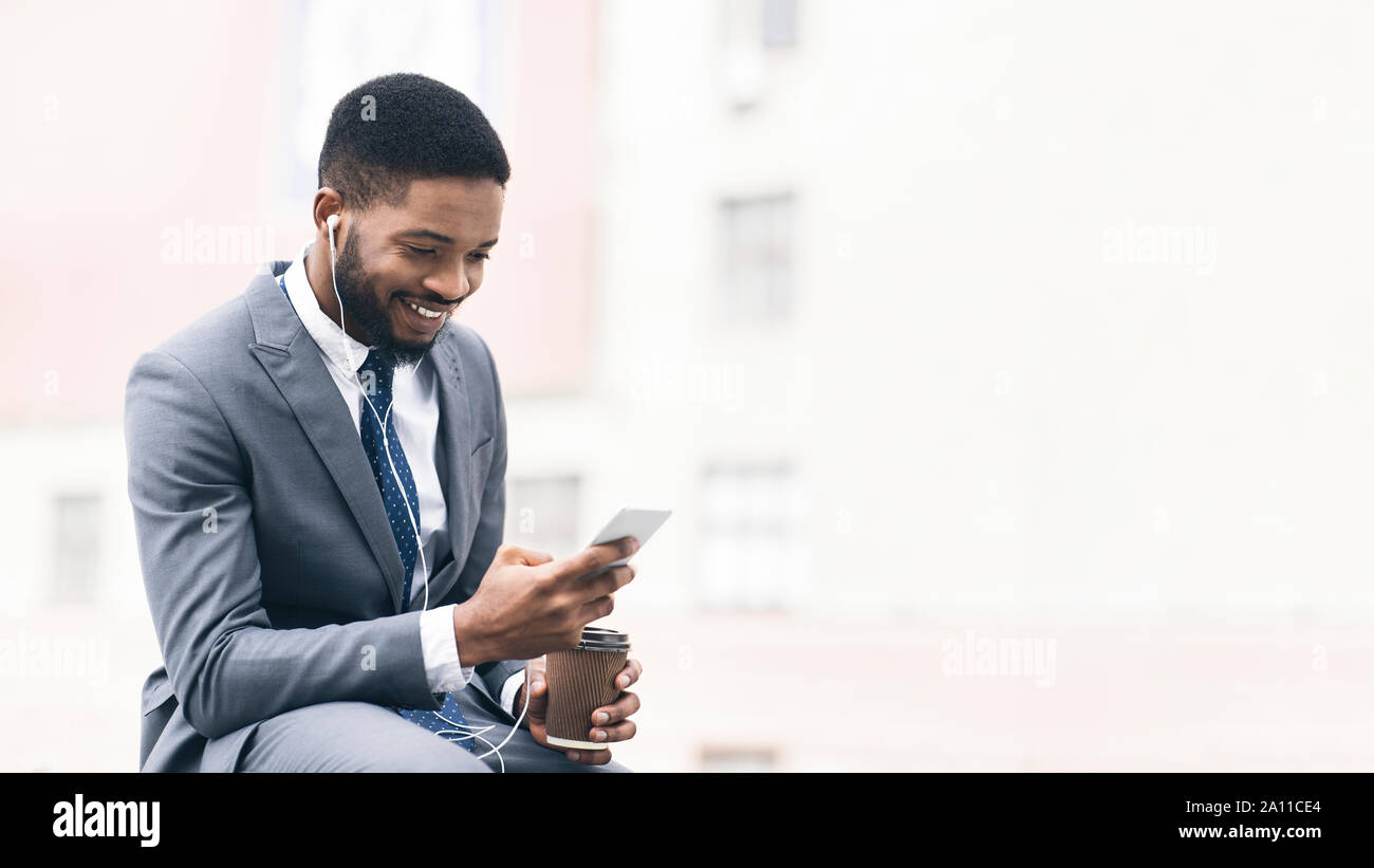 Businessman with coffee using cellphone near office Stock Photo