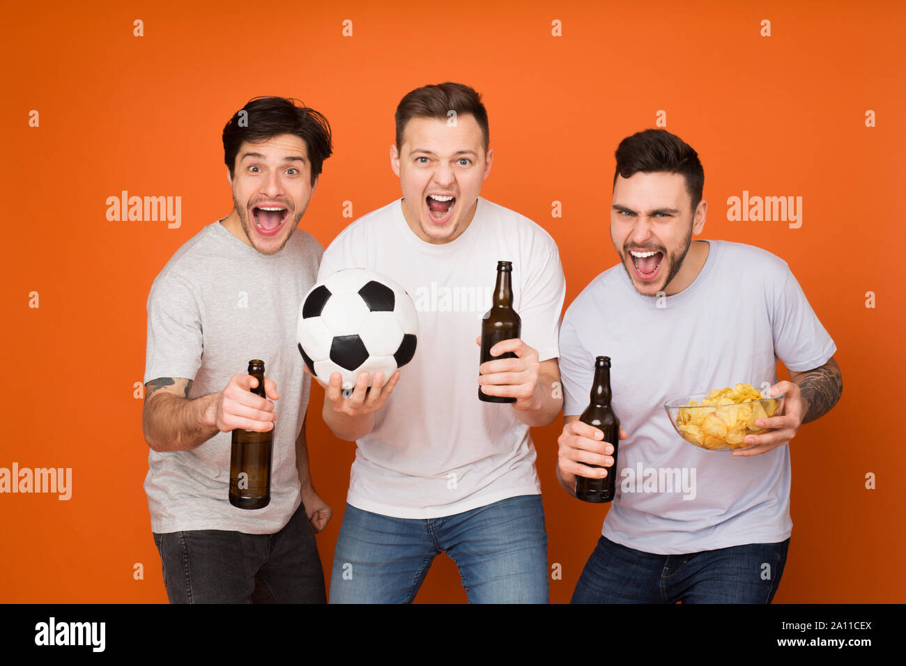 Excited football fans watching match with beer and snacks Stock Photo