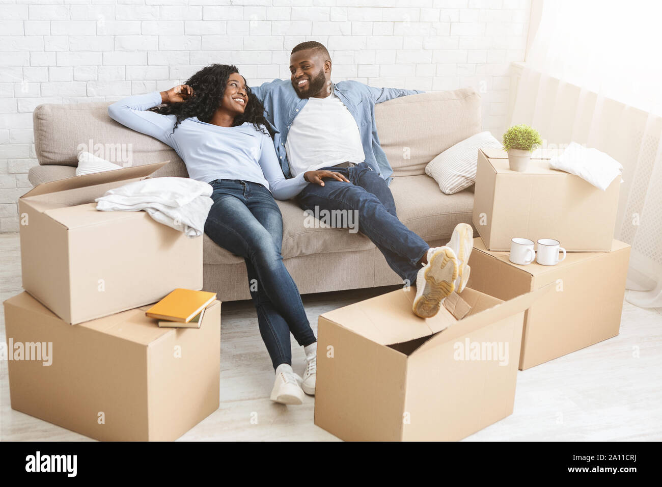 Couple On Sofa Taking Break From Unpacking On Moving Day Stock Photo