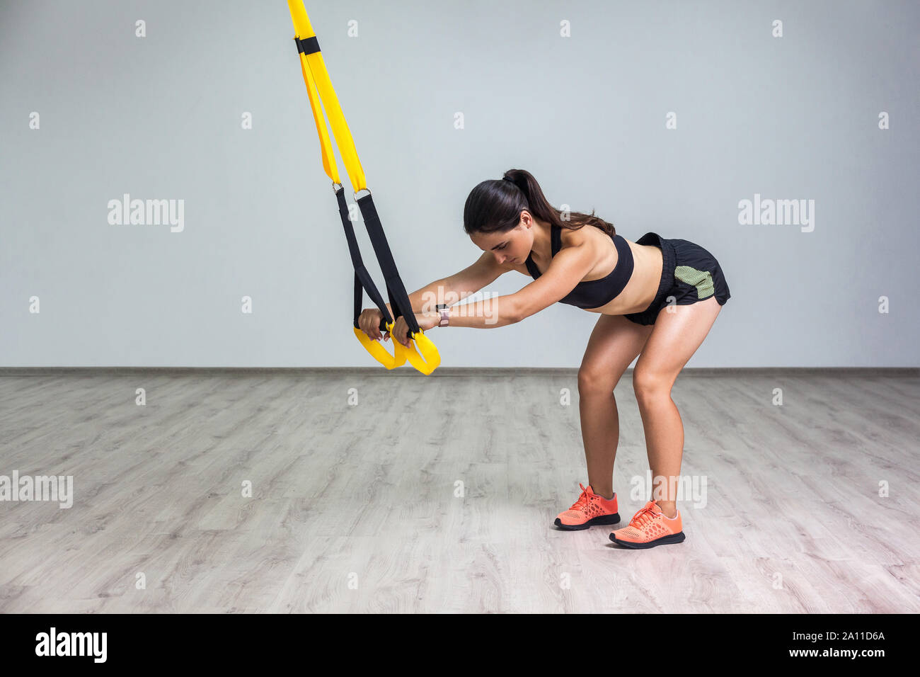 Portrait of young beautiful fit woman in sportswear doing a squat exercise  with fitness straps in the gym. TRX functional training. Sports lifestyle  Stock Photo - Alamy