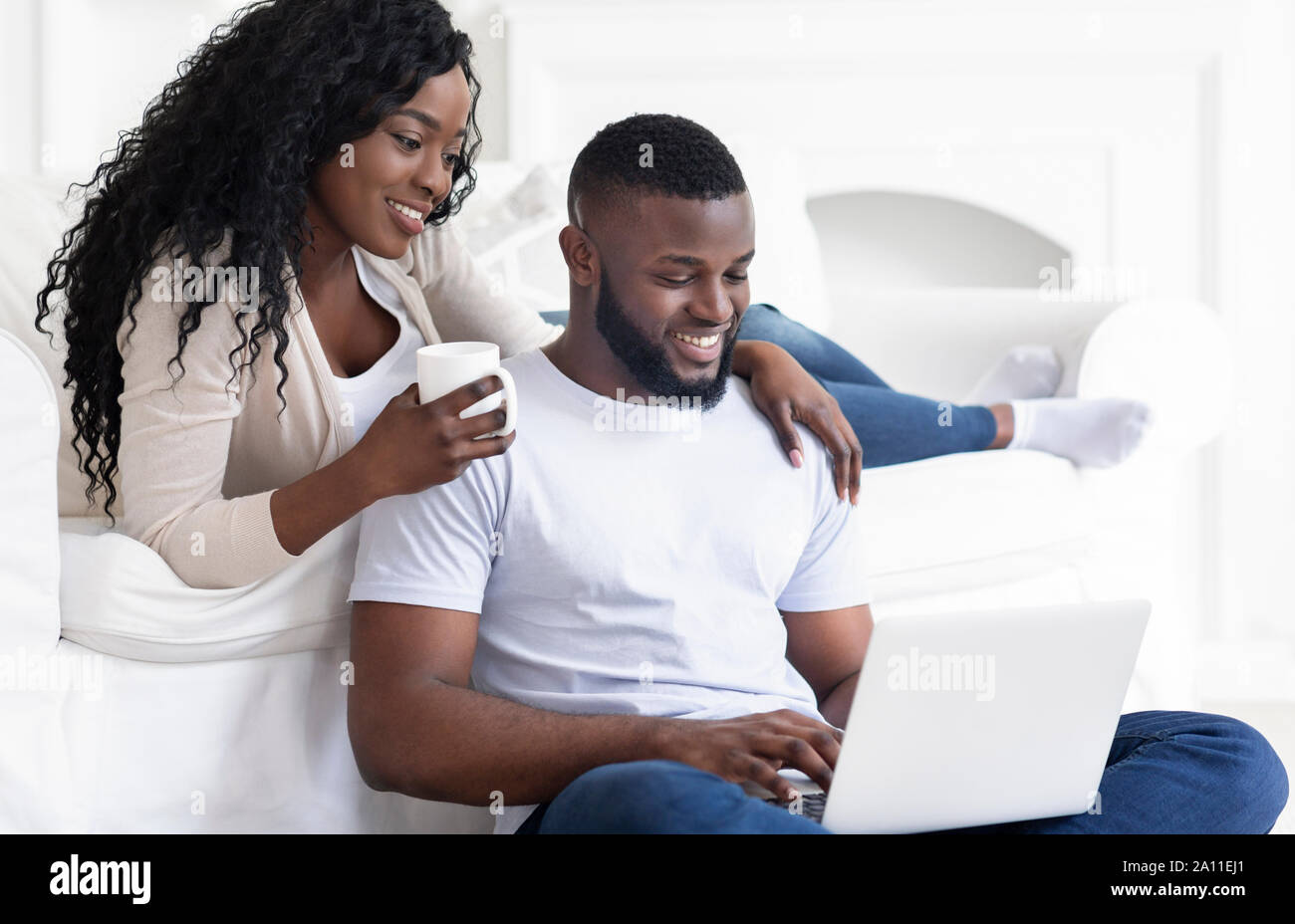 Black couple web surfing on laptop while sitting at home Stock Photo